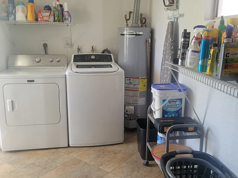 Washer, dryer, and cleaning products in laundry room off of the back patio.
