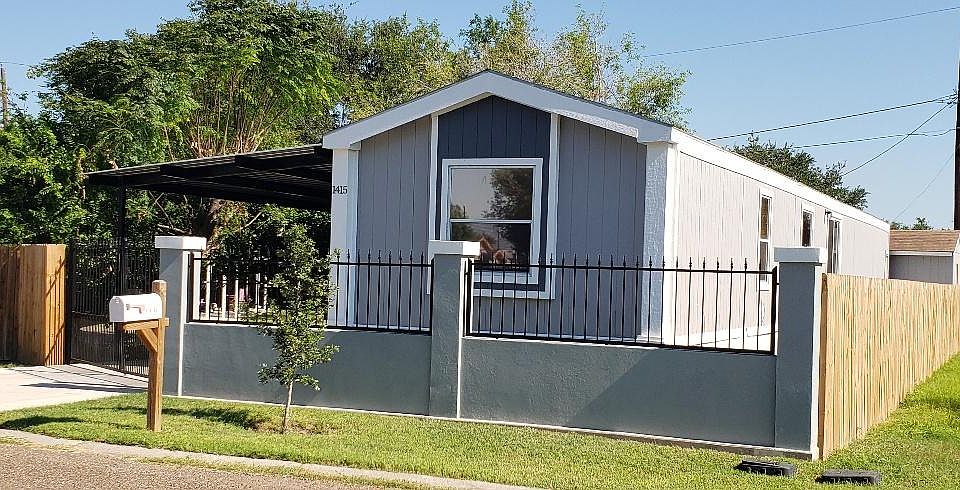 Beautifully remodeled mobile home with wooden fencing on side and rear and stucco and iron-gated front fence. Chain link fencing on opposite side.