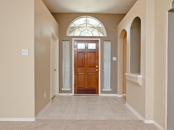 The foyer includes ceramic tile flooring, high ceilings with decorative ledges, a light fixture and an arched art niche' for displaying your favorite items.