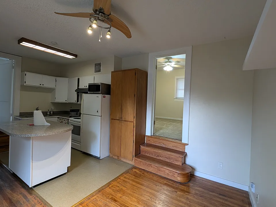 Photo of the kitchen space with one set of steps up to one of the two larger rooms.