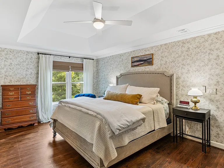 Primary bedroom with a comfortable King bed, room-darkening shades, a ceiling fan, closet, and ensuite bathroom.