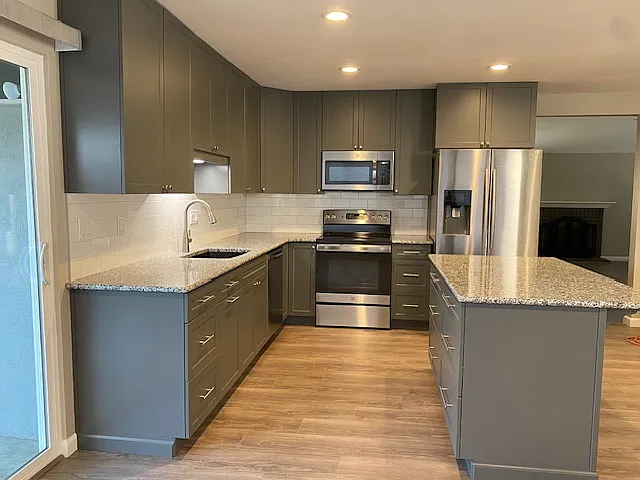 Remodeled kitchen with stainless steel appliances, granite countertops, tile backsplash and island.