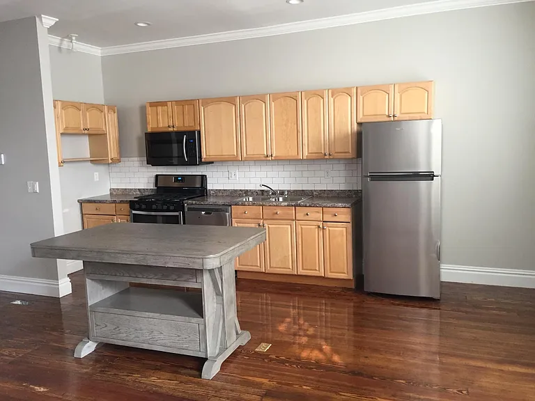 Kitchen cabinetry, stainless steel appliances, including dishwasher, sink, refrigerator. Equipped with microwave and cooktop/oven.