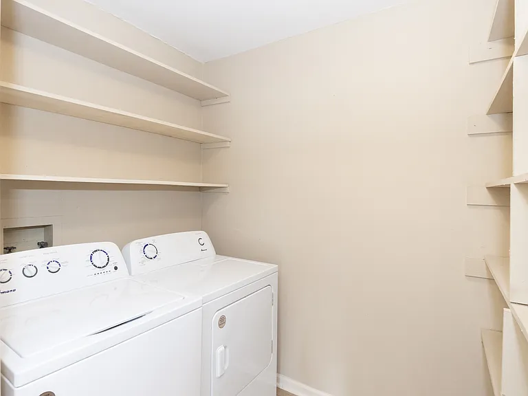 Laundry room with washer and dryer and shelf space above.