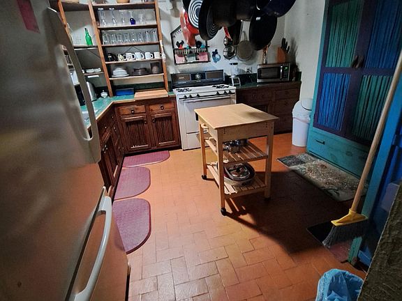 complete kitchen with hand-laid patterned brick floor and pot rack above rolling prep island.