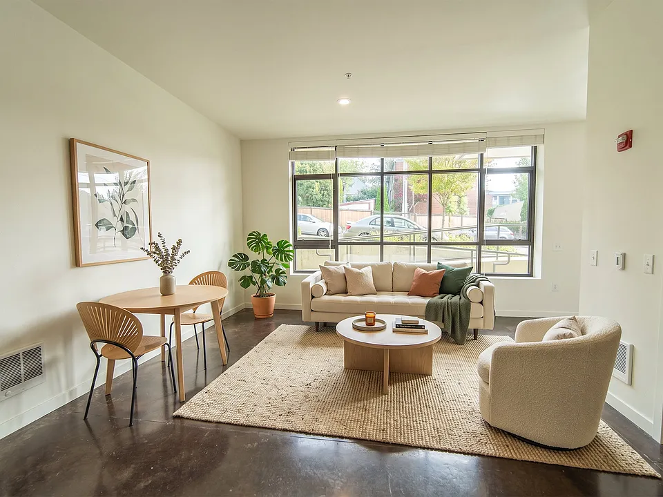 Open living space at Vibe Apartments in Seattle featuring polished concrete floors, large windows, and room for a dining table.