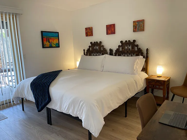 Secondary Bedroom in king bed configuration with hand-carved Spanish revival style headboard and nightstands from Mexico