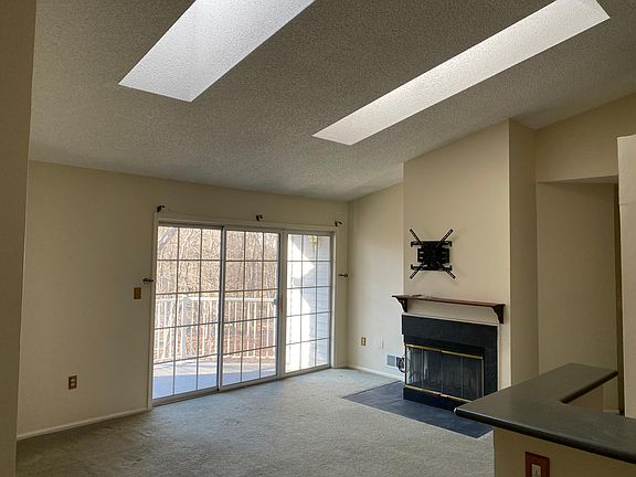 Living room with cathedral ceiling, skylights, and patio door to balcony