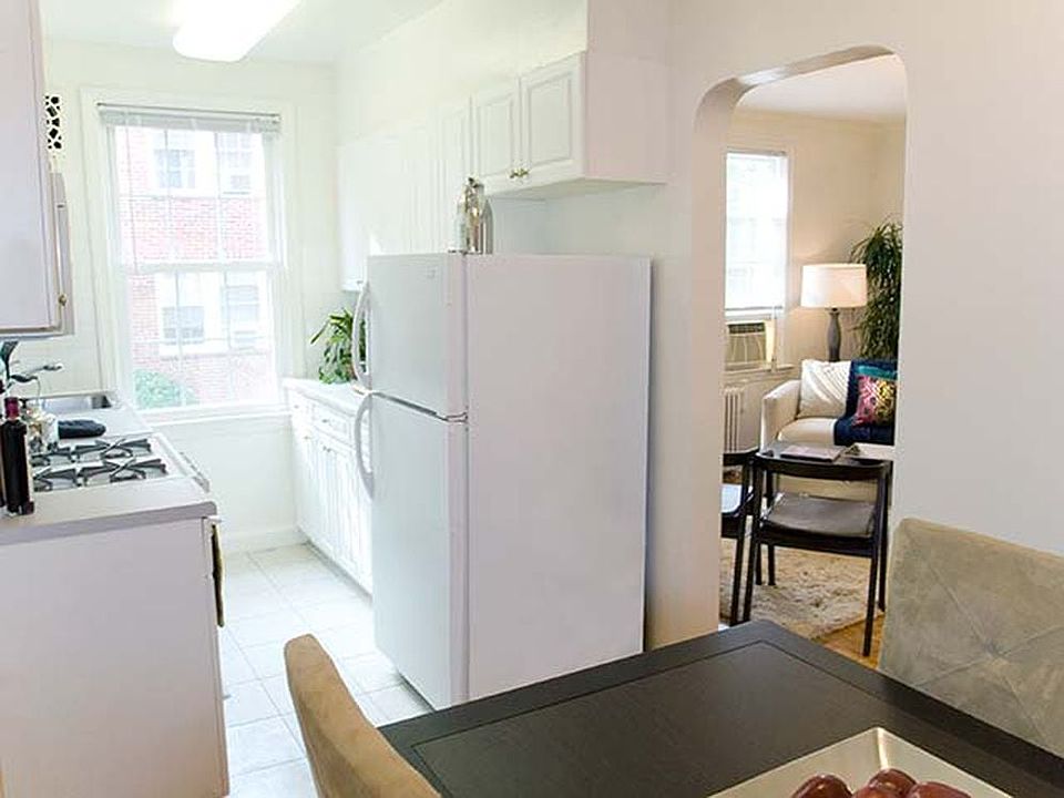 Kitchen and dining area with white appliances, white countertop, white cabinetry and hard surface flooring