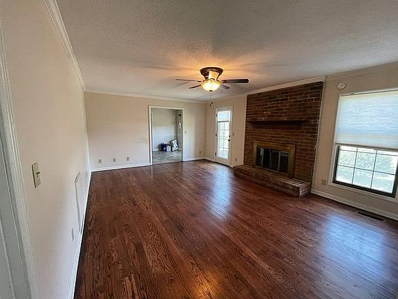Living room with fireplace which leads to breakfast nook and kitchen