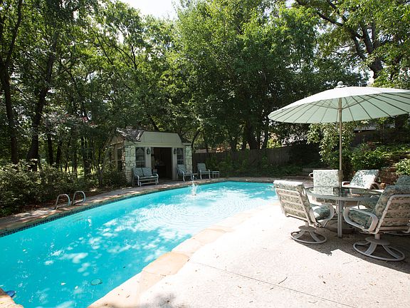 Heated gunite pool nestled beneath a canopy of mature trees backing to permanent greenbelt with walking trail. Charming stone pool house features wood burning fireplace, stained glass windows and newer roof!