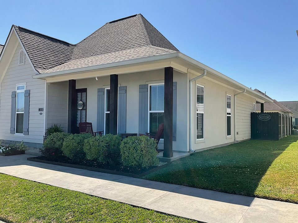 Front of home with side yard. Privacy fence encloses back yard. Front porch faces pond.