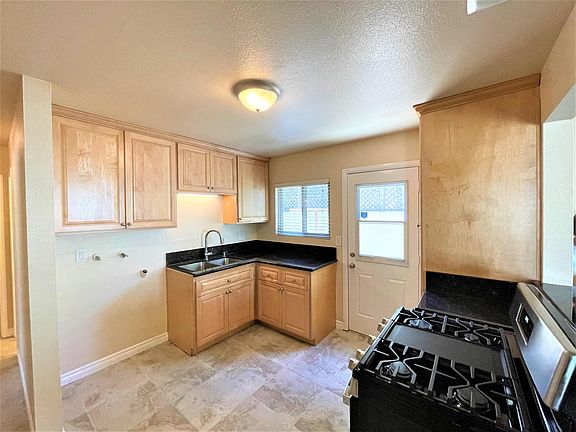 Kitchen with tile flooring, maple cabinets, granite counters and new stainless range and washer hookups.
