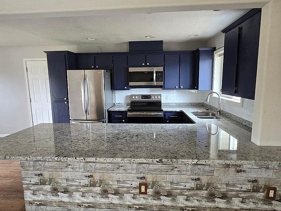 Kitchen with granite counters, newer stainless steel appliances. Door leads to laundry and attached garage.