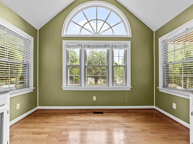 Eat-in kitchen with vaulted ceiling, oversized arched window, and abundant natural light.