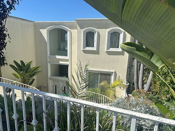 Graceful spiral staircase descends to a private entry framed by tropical foliage and Mediterranean-inspired architecture_offering a dramatic yet inviting transition into this coastal retreat.