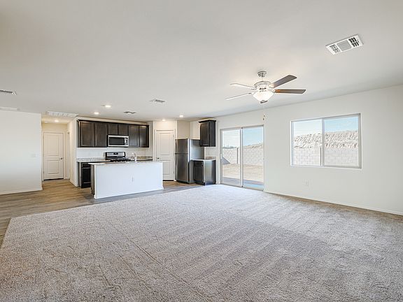 Spacious family room with a ceiling fan, adjacent to the kitchen.
