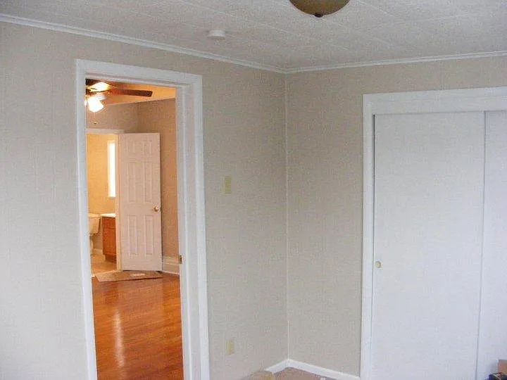 Main floor bedroom with sliding door closet, view into living room and half bath
