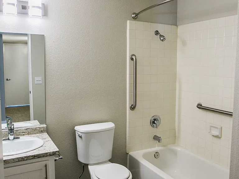 Bathroom with new lighting, wood-style flooring, and space-creating curved shower rod.