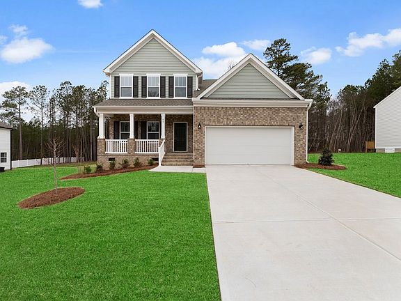 A large house with a white garage door is sitting on top of a lush green lawn.