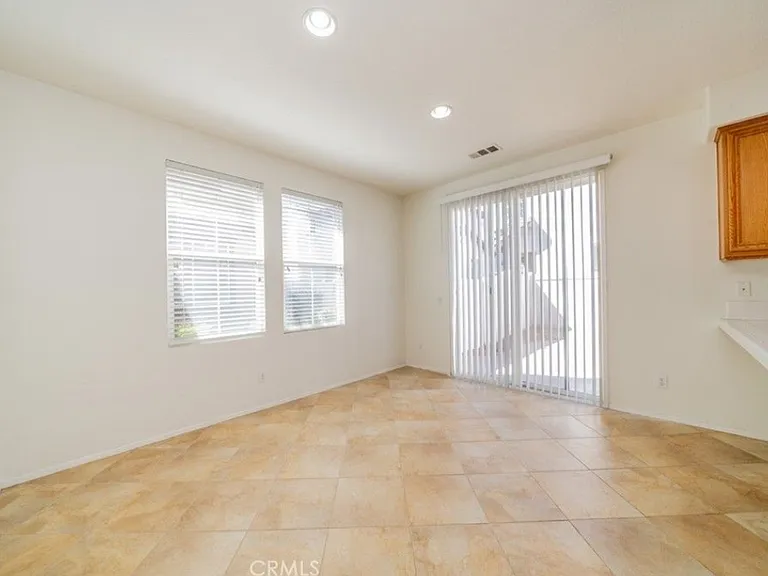 This picture shows the breakfast bar area and large dining room. It also shows the sliding glass door that enters the backyard and two windows that face the front of the house.