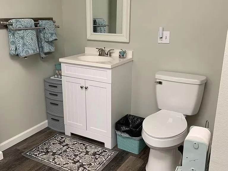 Well-kept bathroom featuring a single-sink vanity with storage, framed mirror, and durable wood-look flooring.