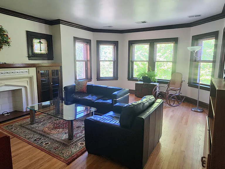 Living Room includes a leather couch and armchair, antique rocking chair, glass coffee table, Oriental rug, two plant stands, credenza, cabinet and large screen TV.
