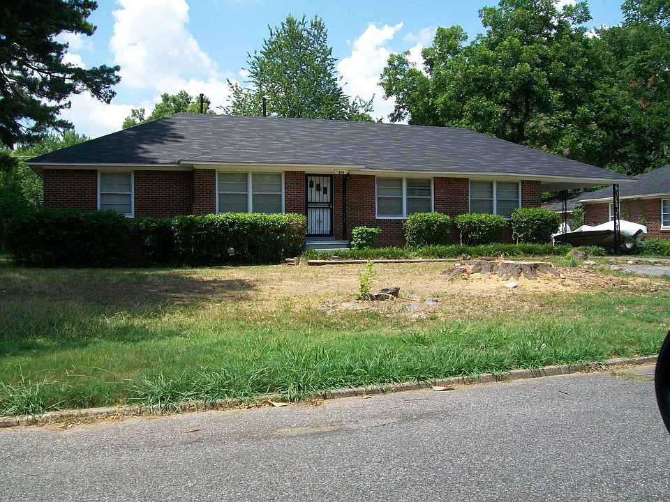 Front of home, fully landscaped with shrubs and a rose bush