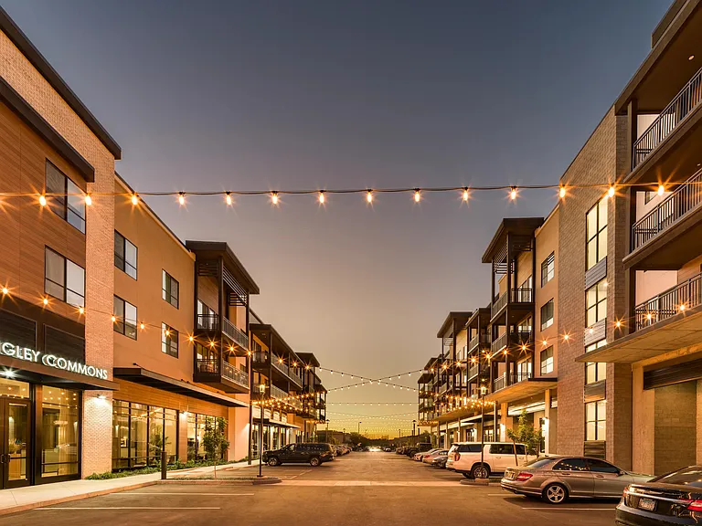 Twilight settles over Modera Higley Commons, where warm lighting and thoughtful design create an inviting streetscape for everyday moments.