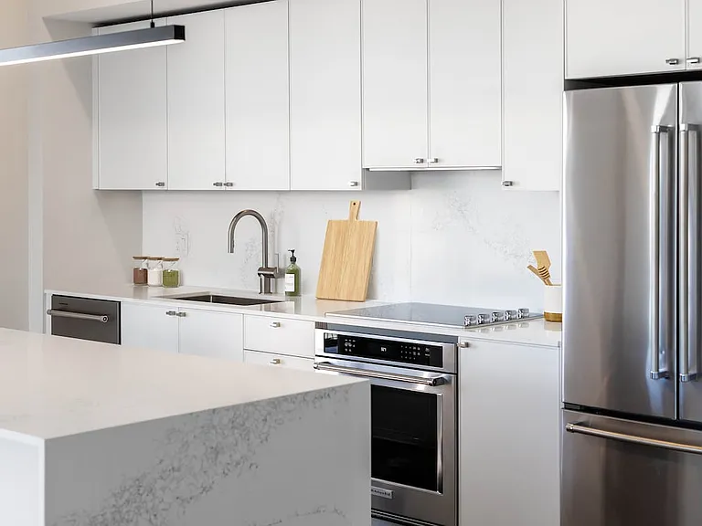 Signature Collection kitchen with white cabinetry, white marbled quartz countertop and backsplash, wine fridge, and upgraded stainless steel appliances