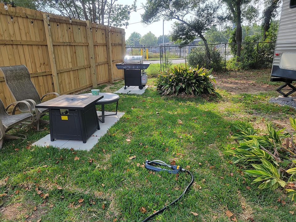 Relax under the trees in the private yard with a gas fire pit table and coffee table plus a gas grill.