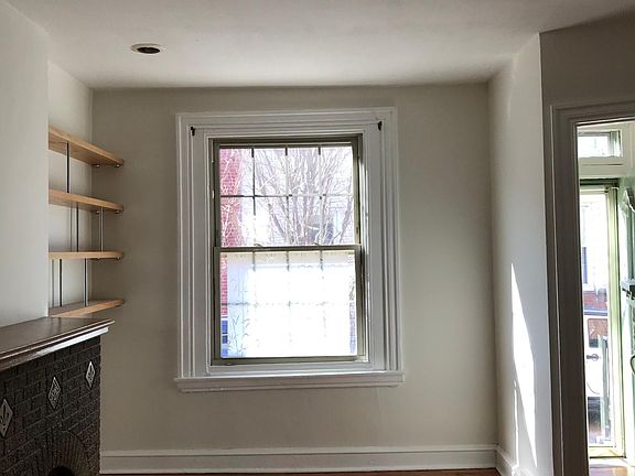 View from the middle of the living room toward the front window. Original decorative fireplace (does not work as a fireplace) hardwood floors are newly polished