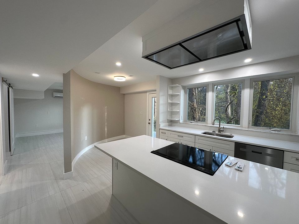 Kitchen with seating at center island & separate dining area along curved wall, with view into bedroom