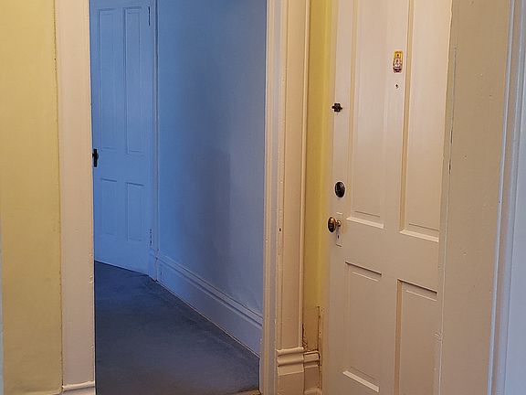 This entry to the Drawing Room apartment features the original wood floor, hand carved wood trim, and an elegant chandelier.