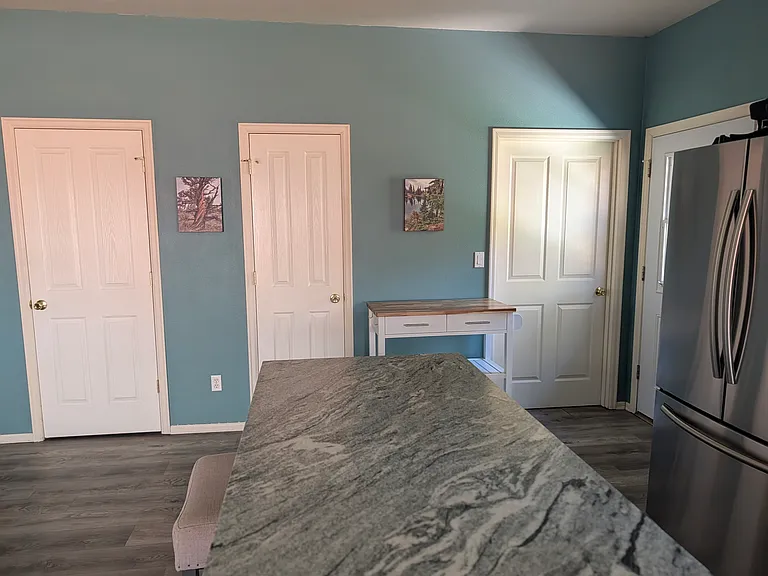 Looking from the kitchen toward pantry, extra storage, and door to washer/dryer and garage. Note new refrigerator.