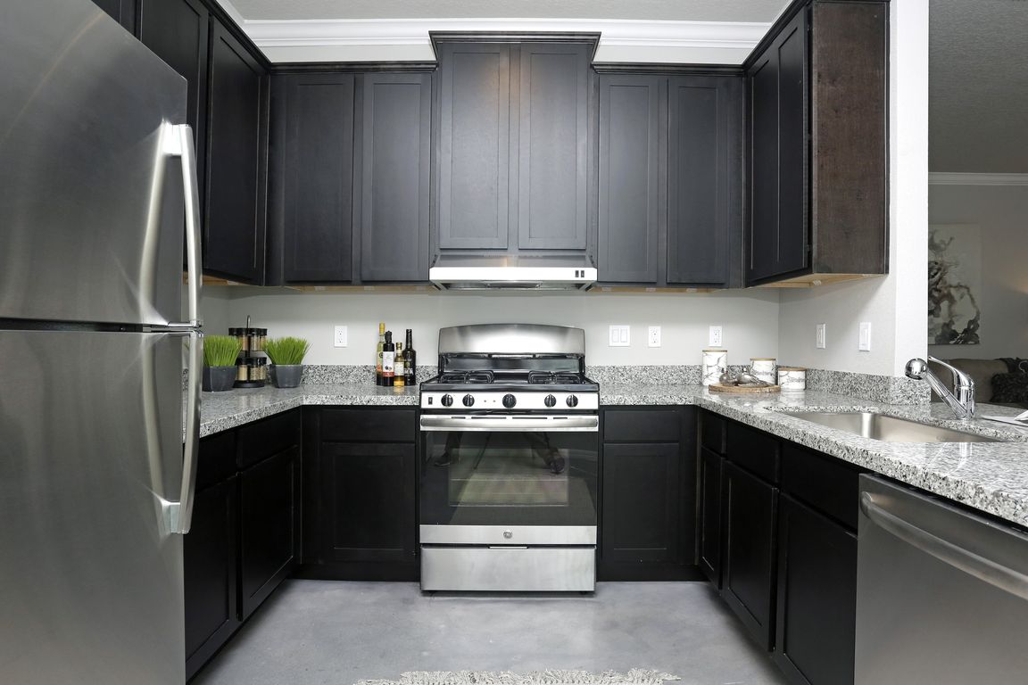 Sleek modern kitchen with stainless steel appliances, granite countertops, and dark cabinetry.