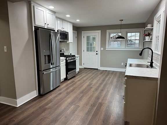 Spacious, fully renovated kitchen featuring modern wood-look plank flooring and abundant natural light.