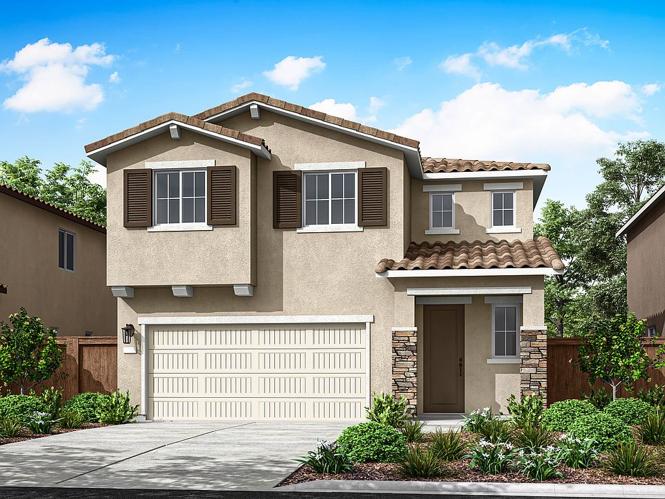 A two-story stucco house with a tiled roof, a garage door, and a well-landscaped front yard surround