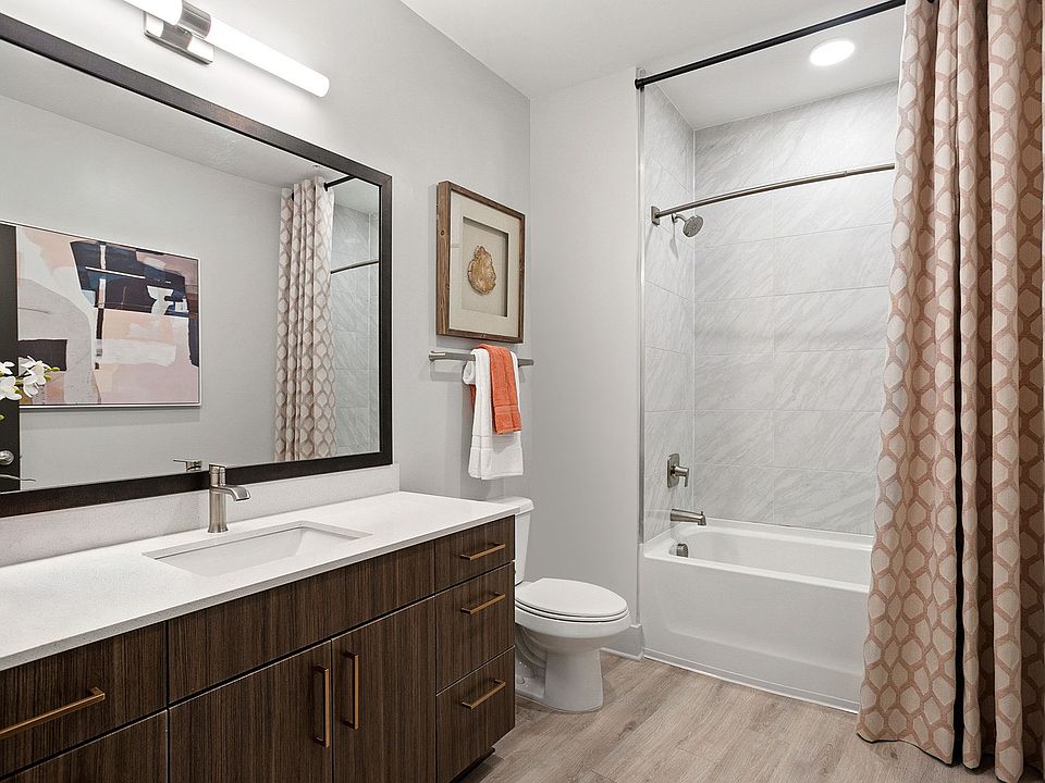 Modern bathrooms with framed mirrors, curved shower rods and quartz countertops