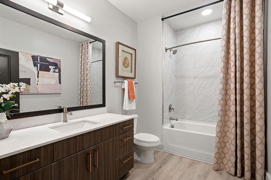 Modern bathrooms with framed mirrors, curved shower rods and quartz countertops