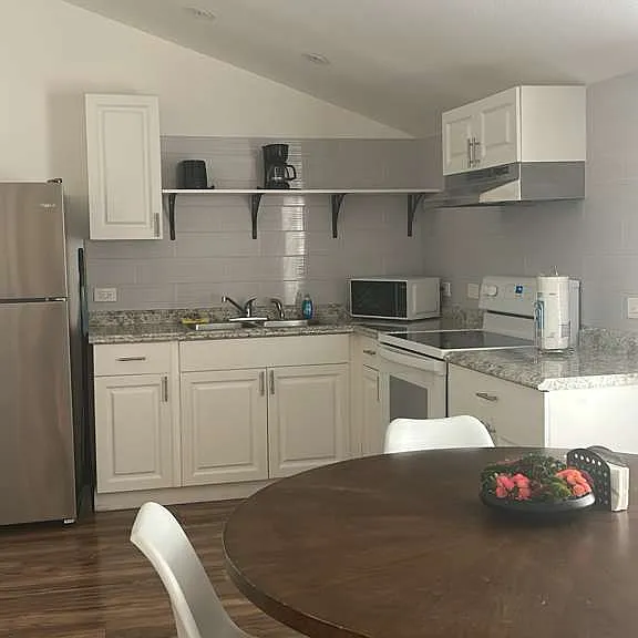 Fully equipped kitchen with cabinets, fridge, coffee maker, microwave, and essentials.