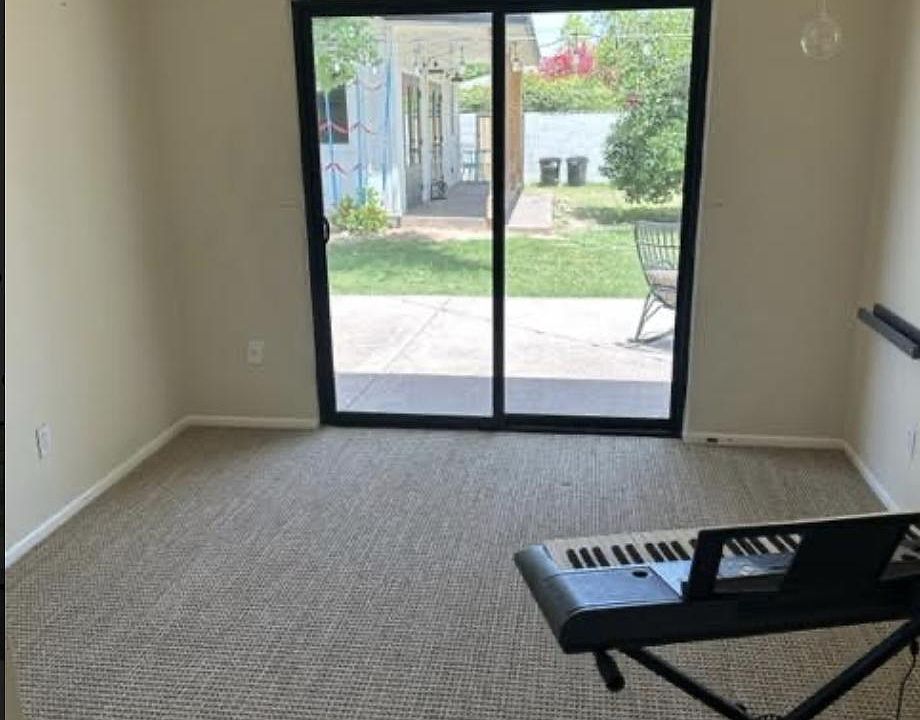 Room looks out to fenced in private yard with grass and mature oak trees with oranges