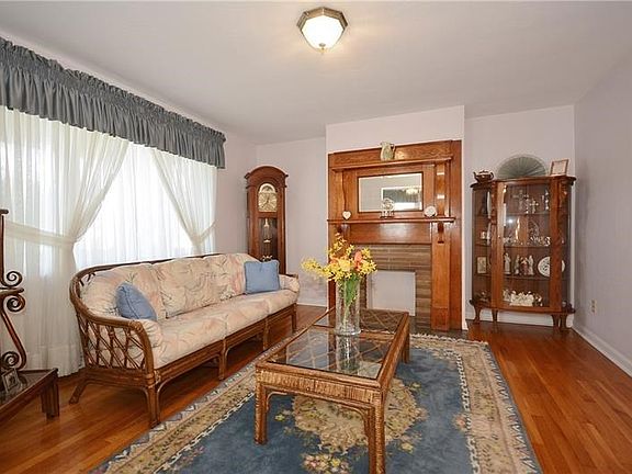 The large window, shining hardwoods, and custom wood fireplace mantle add warmth and elegance to the living room.