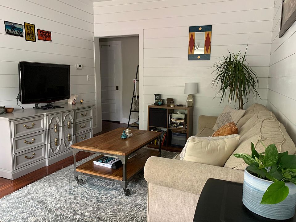 Living room with high 9ft ceilings. Short hall leads to full bath, laundry closet (door visible) and bedroom.