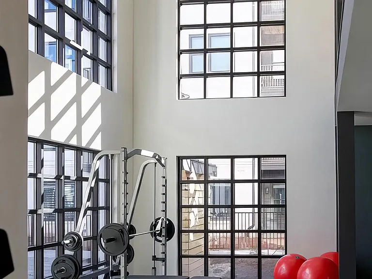 Weight rack with several benches in fitness area with extra tall ceilings