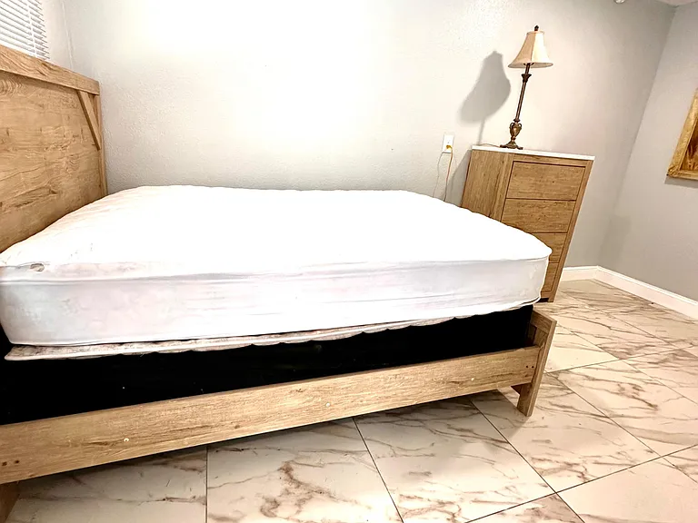 Furnished bedroom with a wood bed frame, matching dresser, and tiled flooring for easy maintenance.