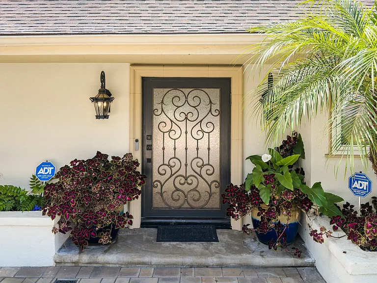 Sconce lighting and potted palms flank the ornate front door of this Beverly Hills luxury rental at 1094 Garden Lane, 90210.