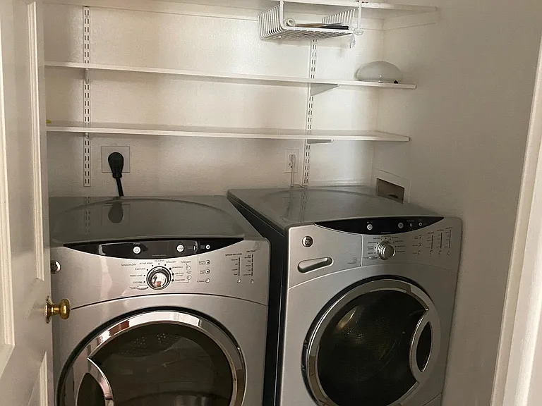 Laundry has front load washer and dryer, utility closet and shelving.