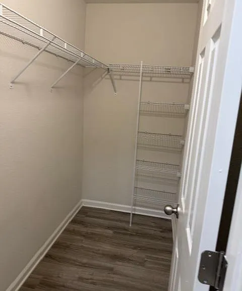 Walk-in closet with wraparound wire shelving and durable plank-style flooring for easy storage and organization.