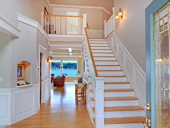 The grand entry foyer that soars 20+ feet to the ceiling above. Note the extensive Ash hardwood floors, the shadow-box wainscoting and the view through the home to the Bay and Poulsbo beyond. Note also, the beveled and leaded glass entry door. The formal living room is to the left and the formal dining room is to the right. The second floor landing is a spacious 12' x 18'